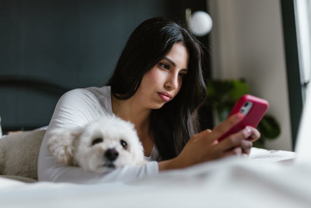 woman scrolling on her phone while laying in her bed